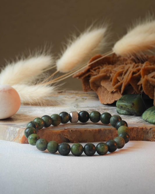 Bracelet en jade verte naturel pose sur roche lisse avec epis blancs et pierre polie de jade verte