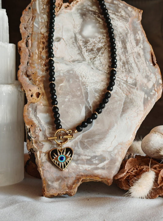 Collier oeil de vision posé sur un présentoir en roche