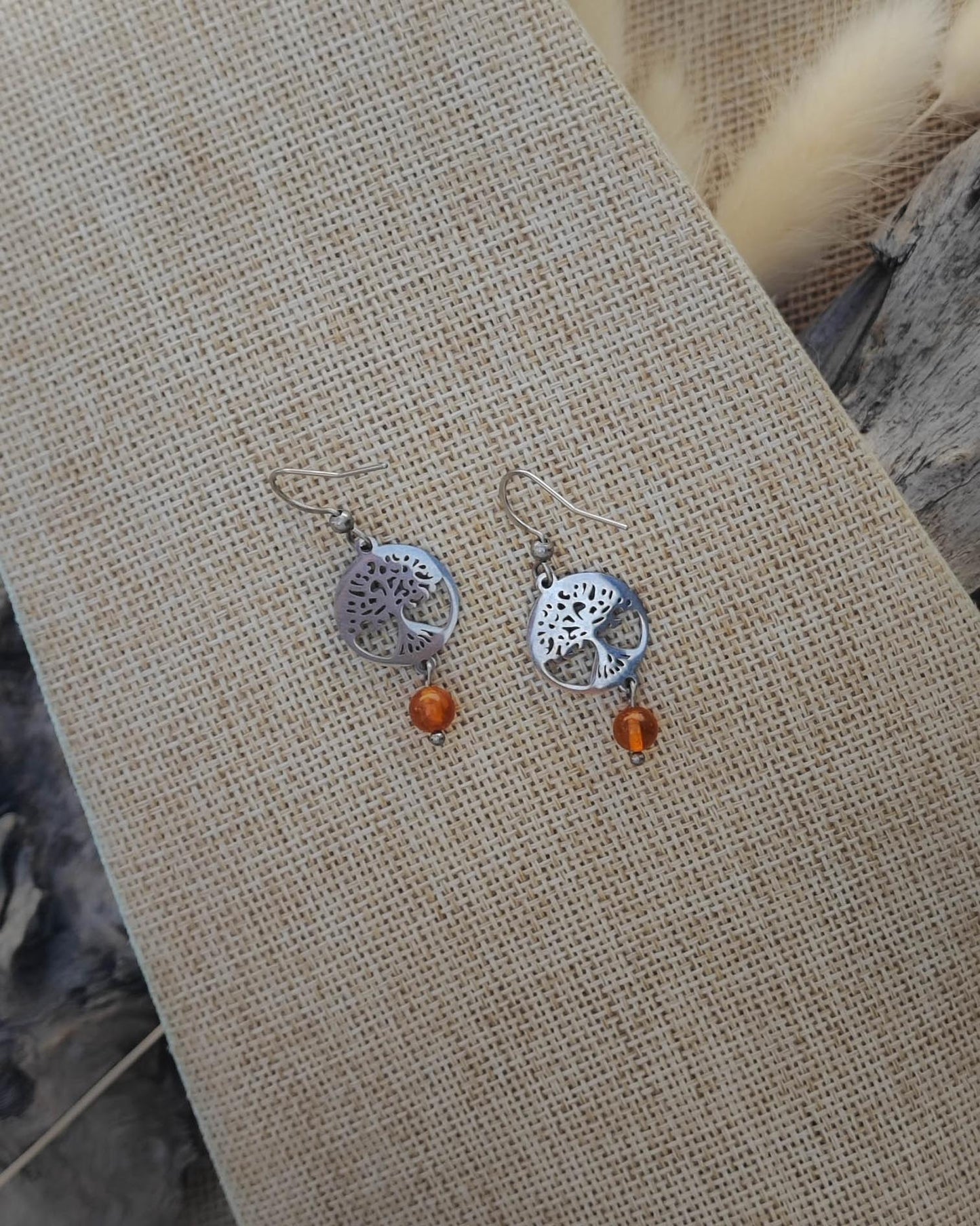 Vue de dessus des boucles d’oreilles Cornaline Arbre de Vie en acier montrant les détails de la pierre et du symbole