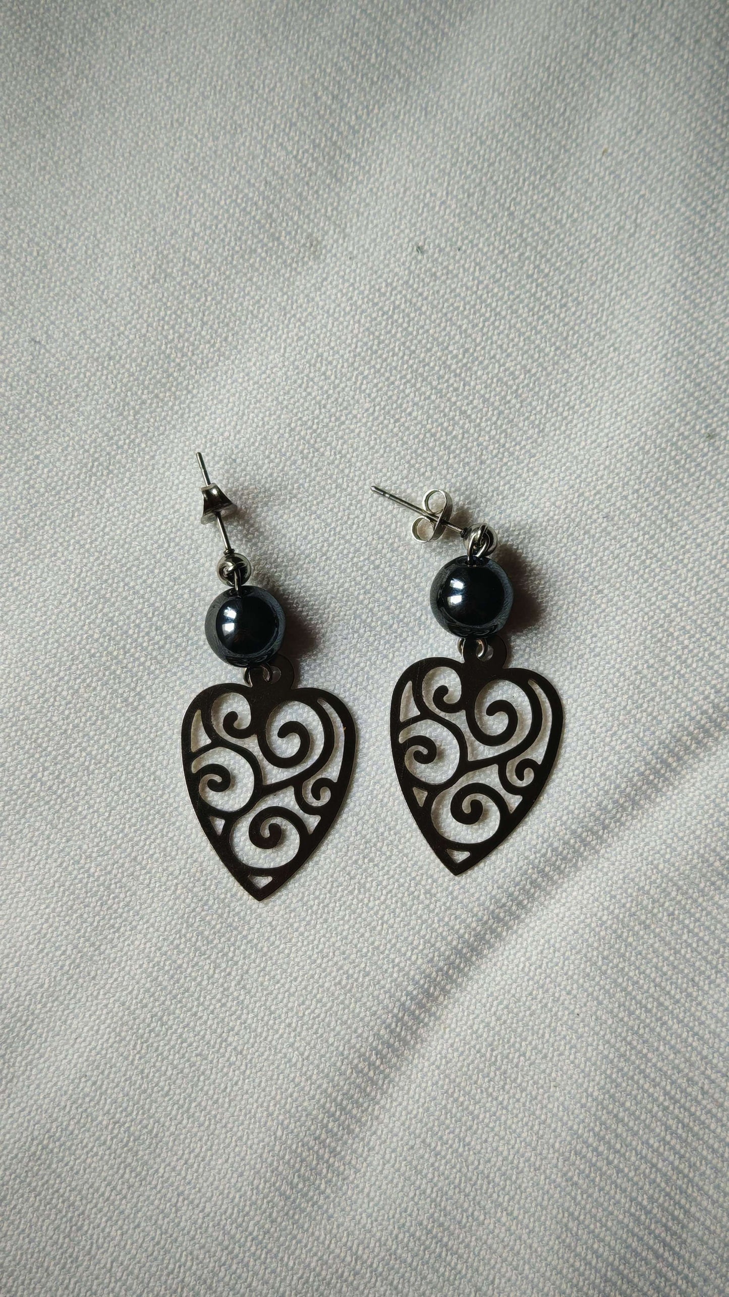 Boucle d'oreille hematite bouclier sur tissus blanc