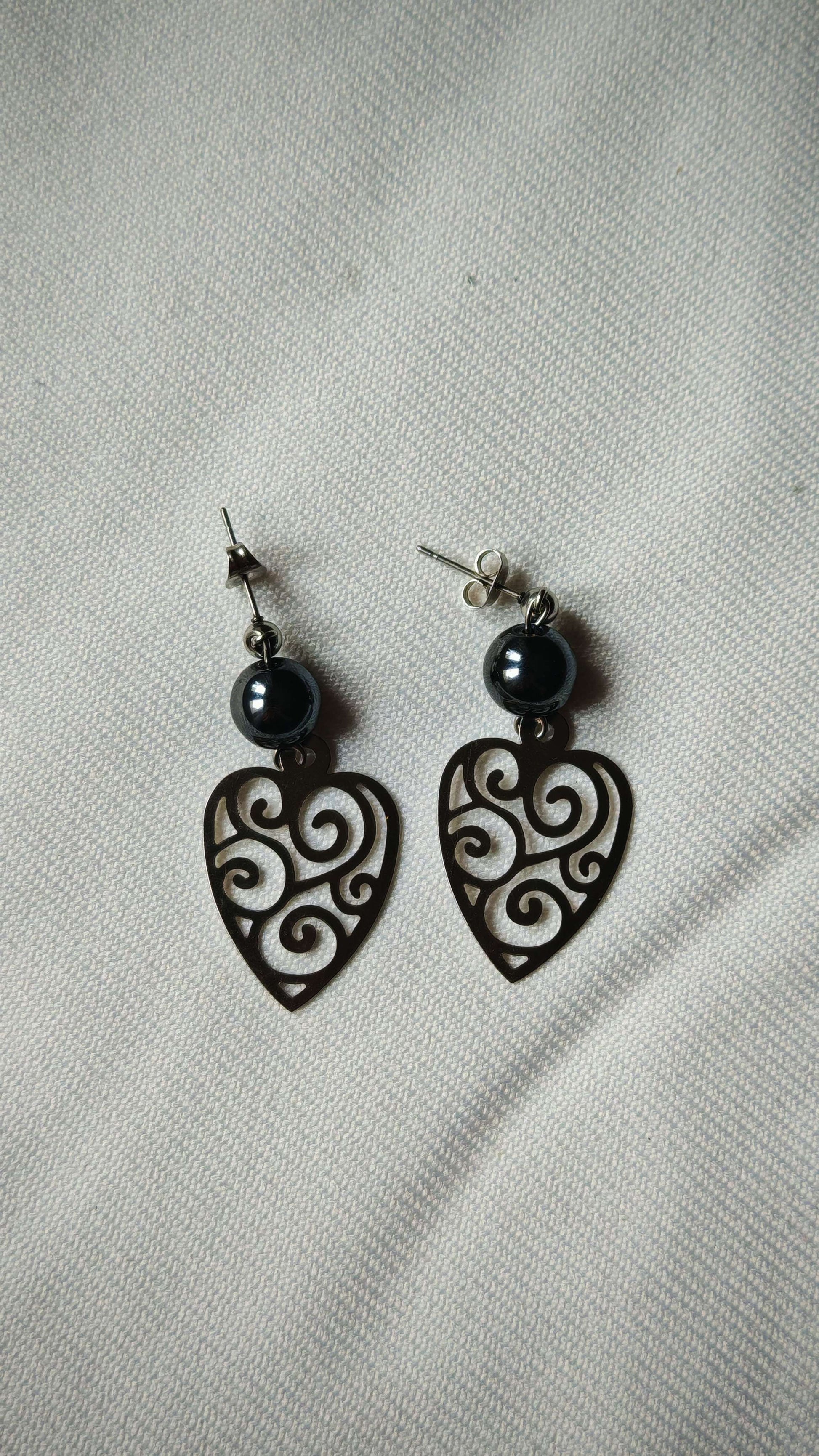 Boucle d'oreille hematite bouclier sur tissus blanc