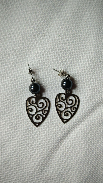 Boucle d'oreille hematite bouclier sur tissus blanc