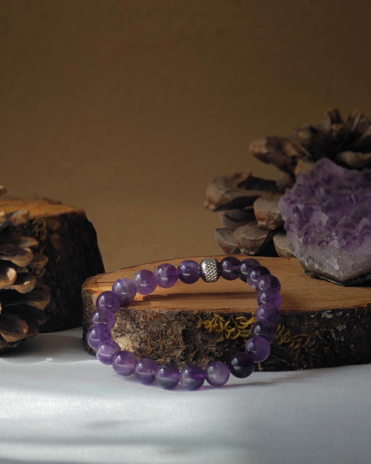 Bracelet en amethyste naturel pose sur rondelle de bois avec pomme de pin et pierre polie d amethyste