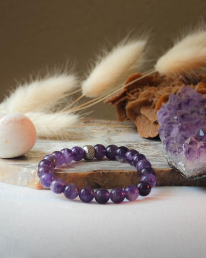 Bracelet en amethyste naturel pose sur roche lisse avec epis blancs et pierre polie d amethyste