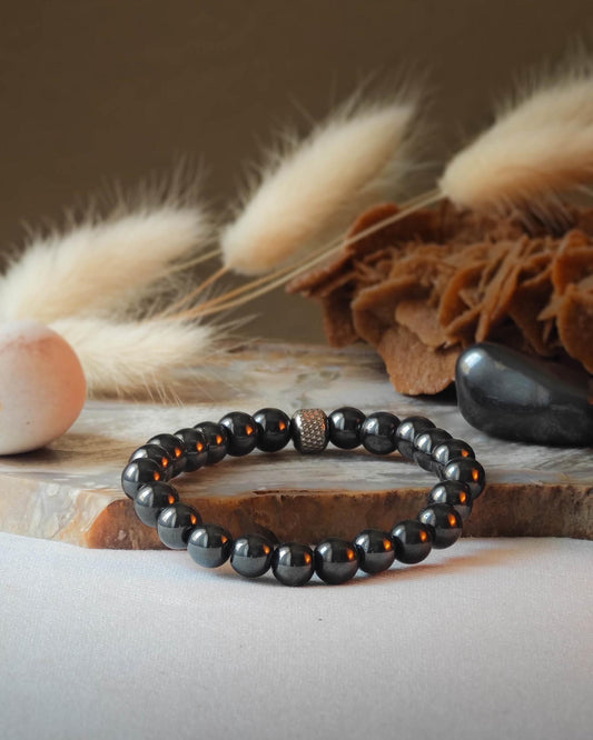Bracelet en hematite naturel pose sur roche lisse avec epis blancs et pierre polie d hematite