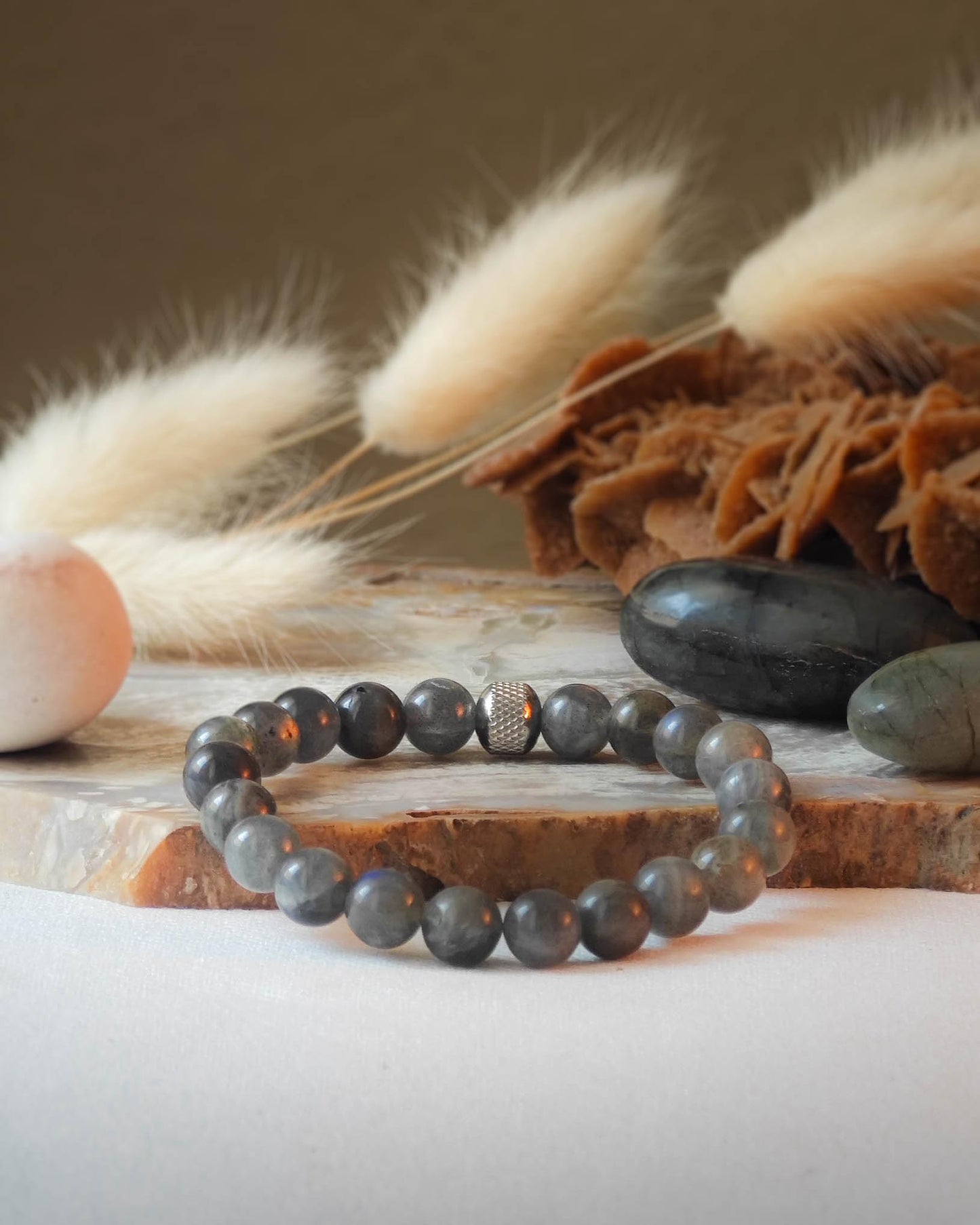 Bracelet en labradorite naturel pose sur roche lisse avec epis blancs et pierre polie de labradorite