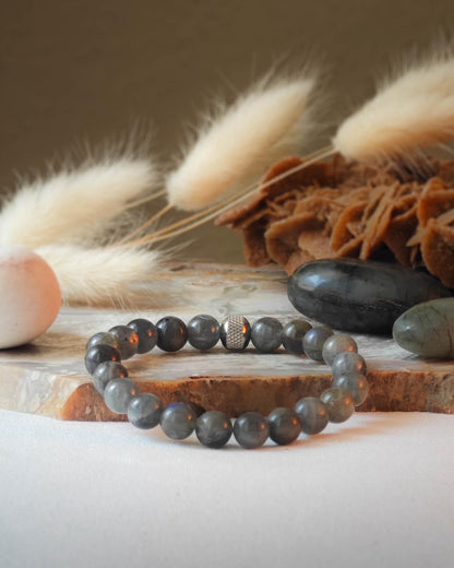 Bracelet en labradorite naturel pose sur roche lisse avec epis blancs et pierre polie de labradorite