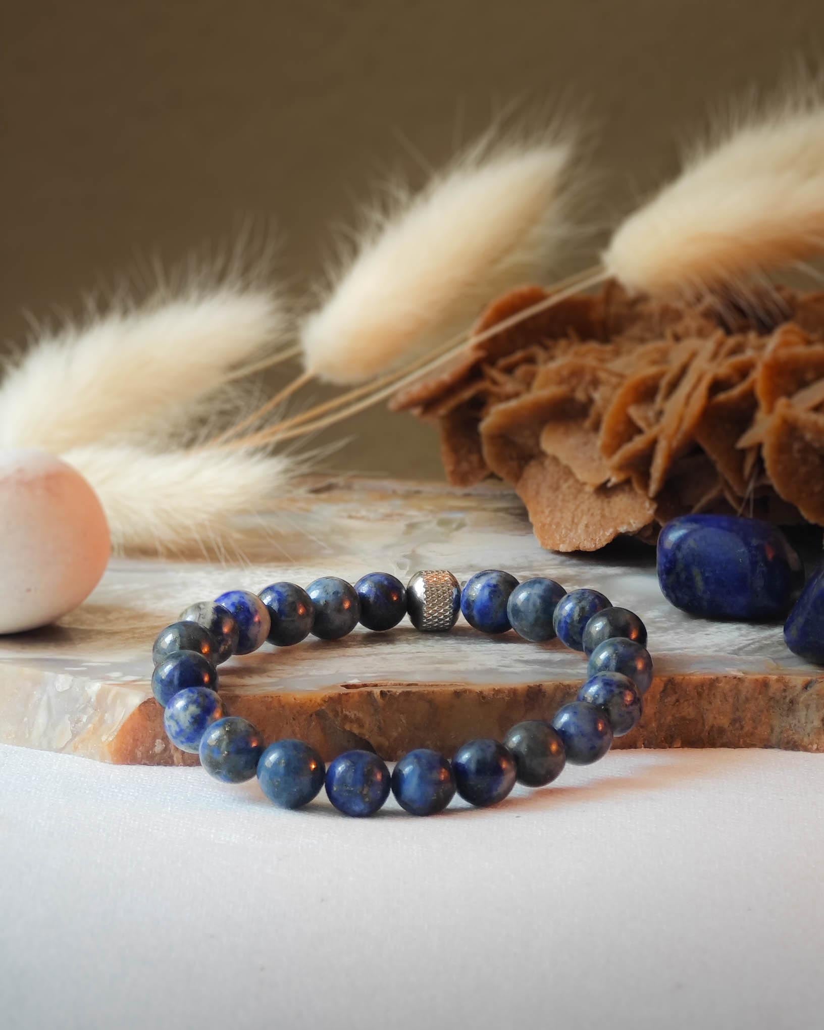 Bracelet en lapis lazuli naturel pose sur roche lisse avec epis blancs et pierre polie de lapis lazuli