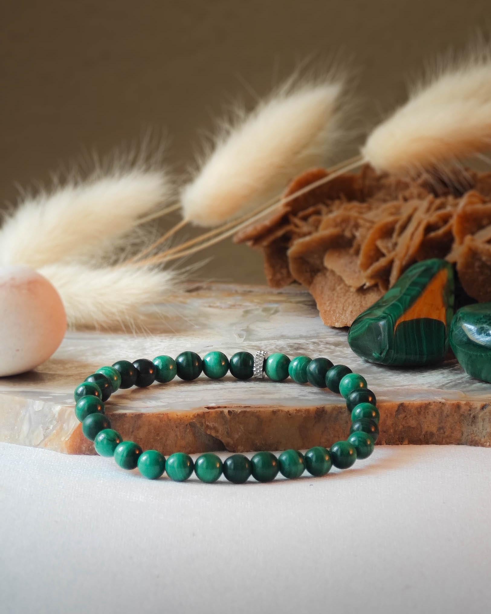 Bracelet en malachite naturelle pose sur roche lisse avec epis blancs et pierre polie de malachite