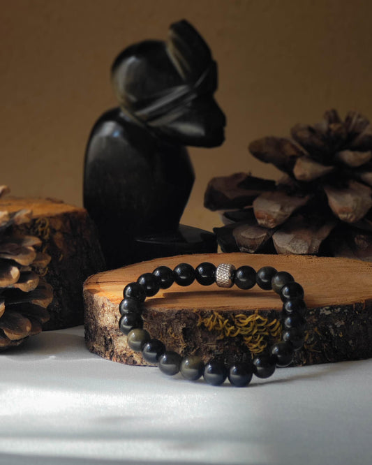 Bracelet en obsidienne doree naturelle pose sur rondelle de bois avec pomme de pin et pierre polie d’obsidienne doree