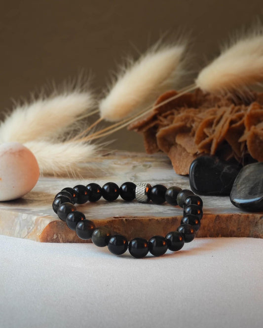 Bracelet en obsidienne doree naturelle pose sur roche lisse avec epis blancs et pierre polie d’obsidienne doree