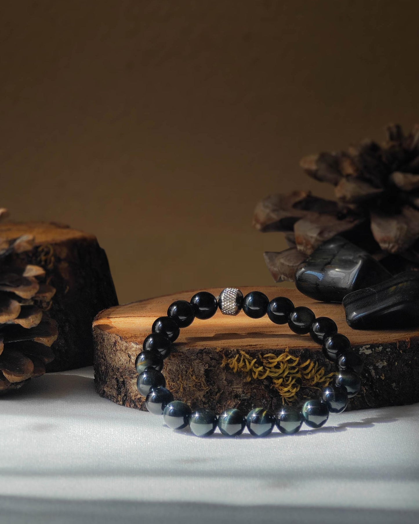 Bracelet en oeil de faucon naturel pose sur rondelle de bois avec pomme de pin et pierre polie d’oeil de faucon