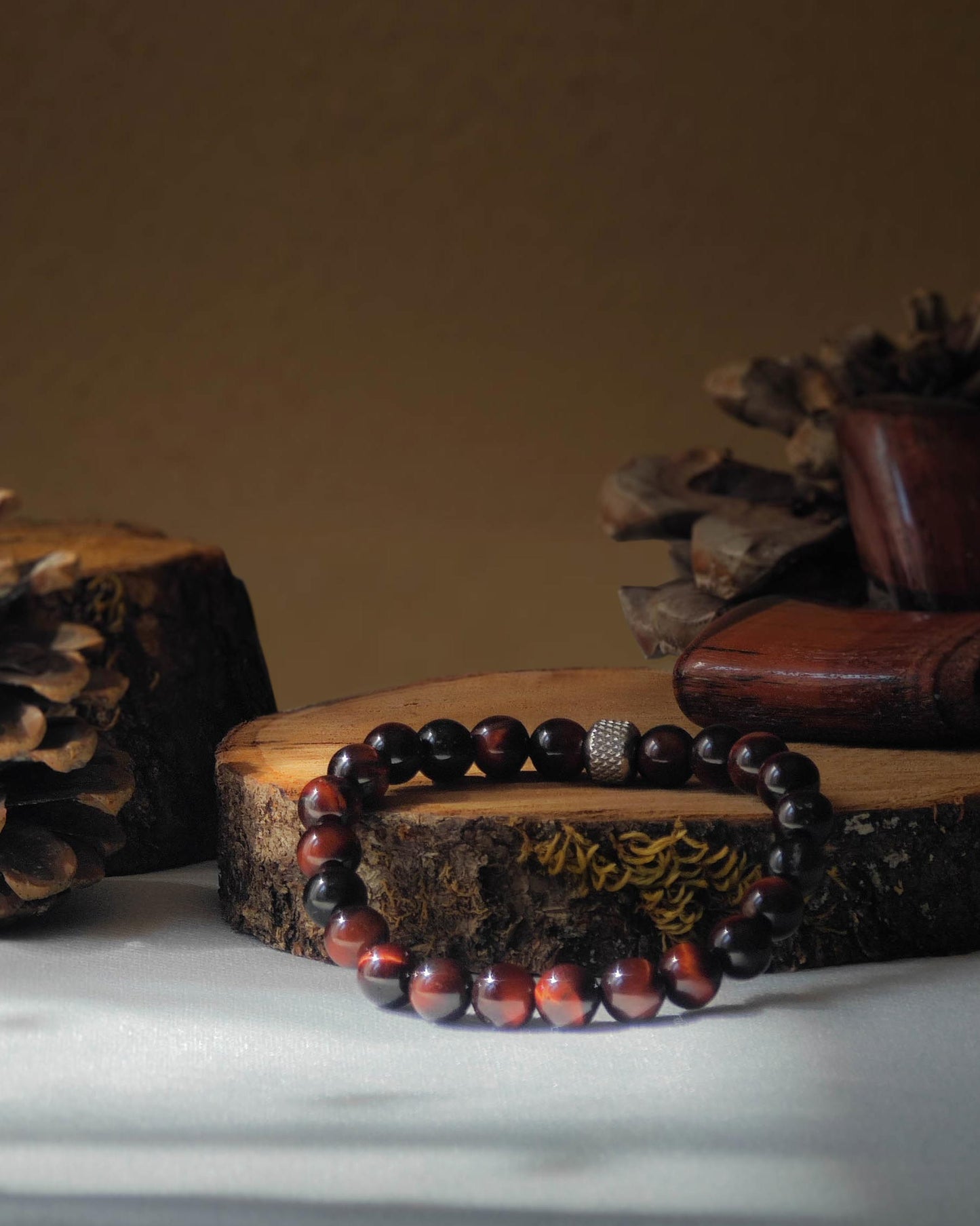 Bracelet en oeil de taureau naturel pose sur rondelle de bois avec pomme de pin et pierre polie d’oeil de taureau