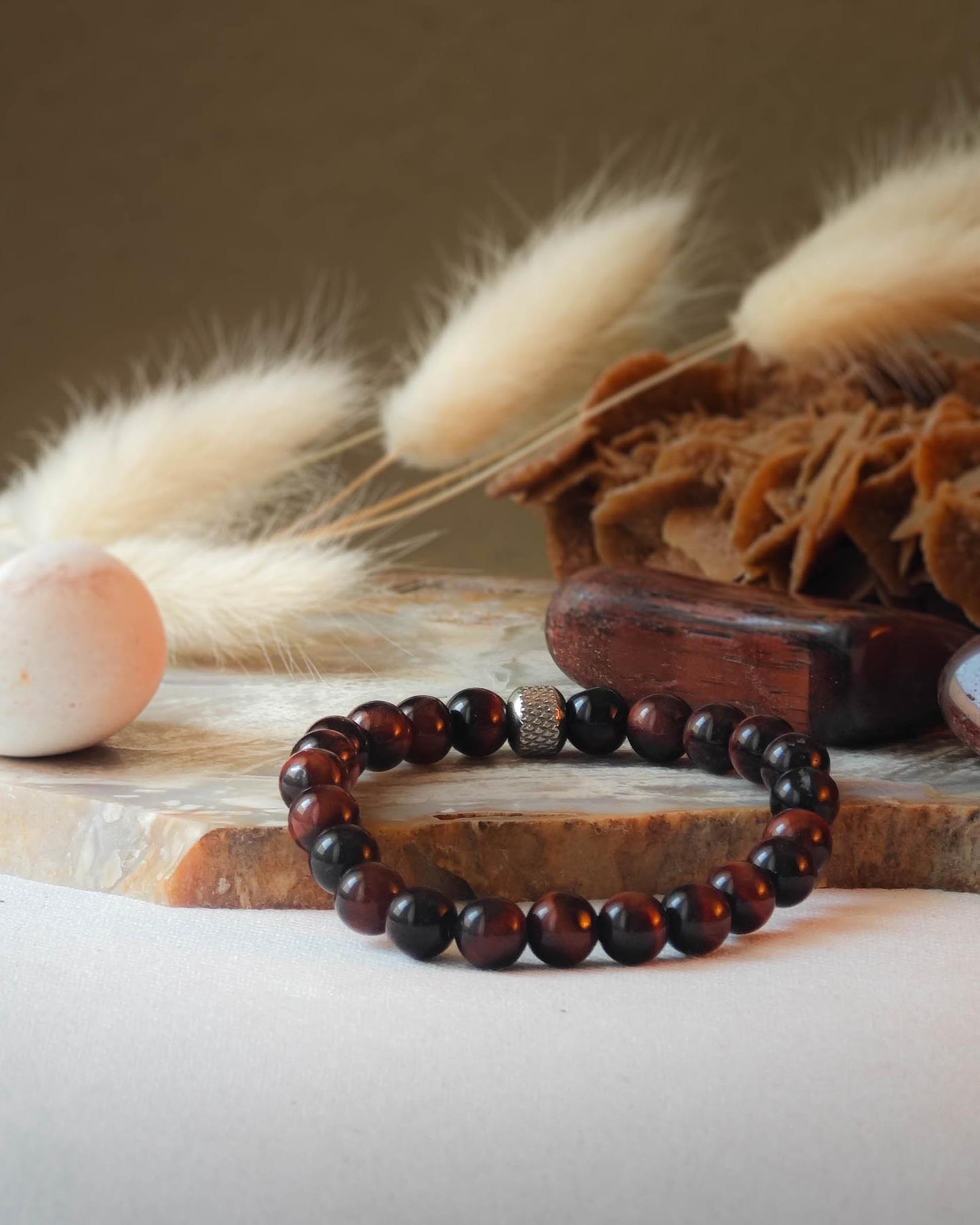 Bracelet en oeil de taureau naturel pose sur roche lisse avec epis blancs et pierre polie d’oeil de taureau