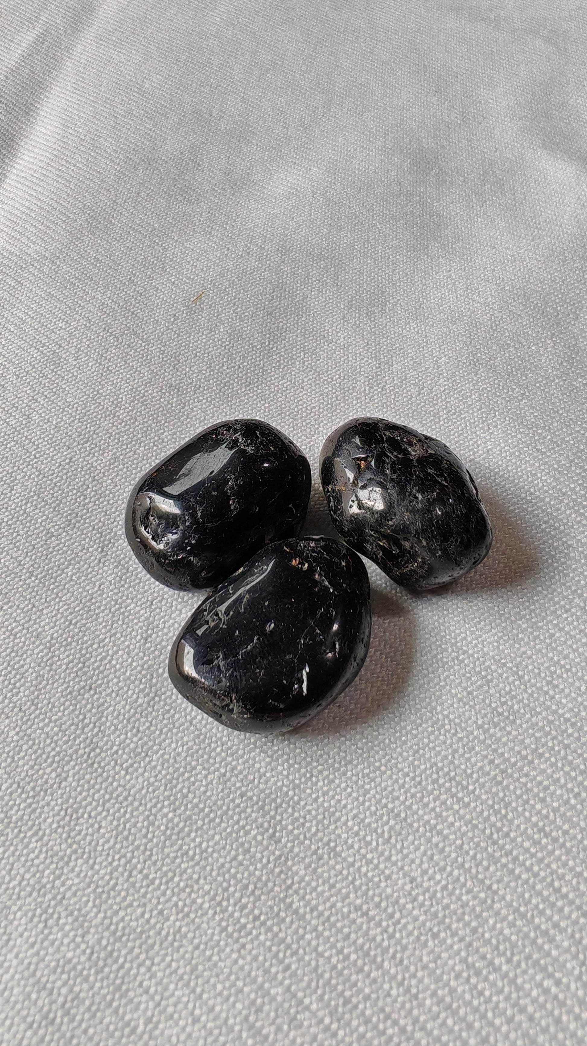 Troumaline noire pierre roulée sur font blanc