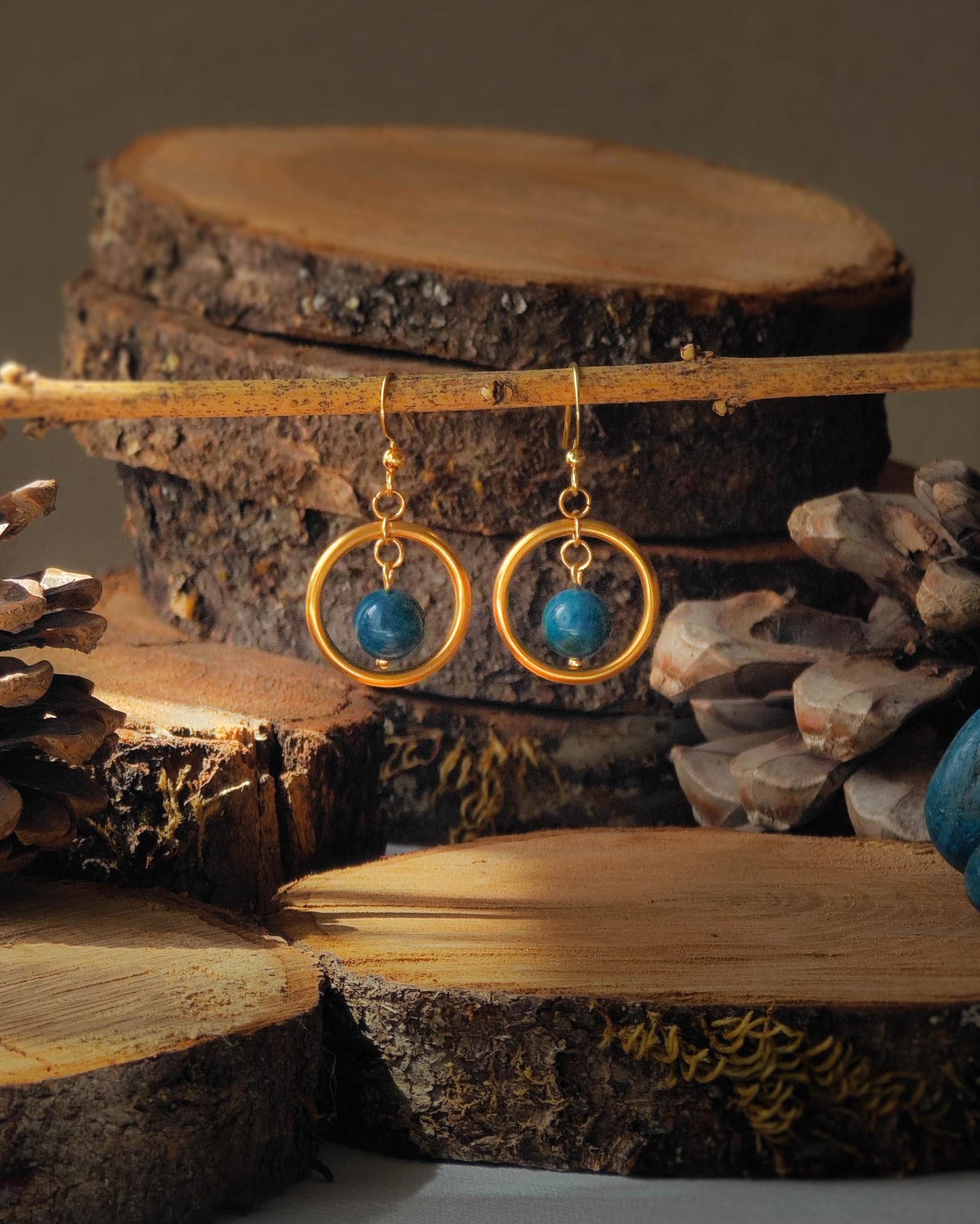 Boucles d’oreilles Apatite créoles dorées sur rondelle de bois avec pomme de pin et pierre apatite