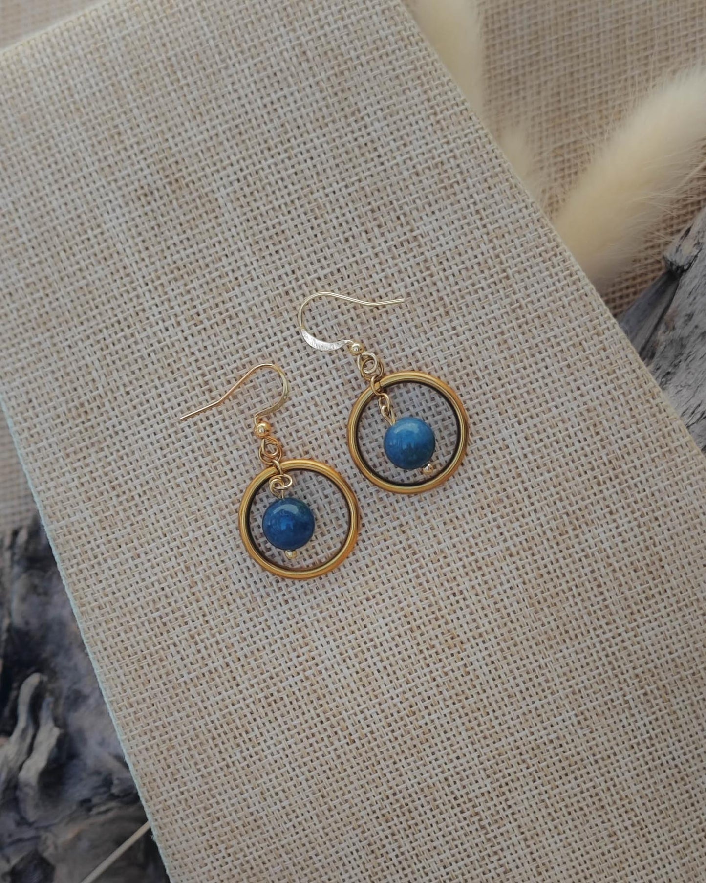 Vue de dessus des boucles d’oreilles Apatite créoles dorées avec détail du cercle et de la perle flottante