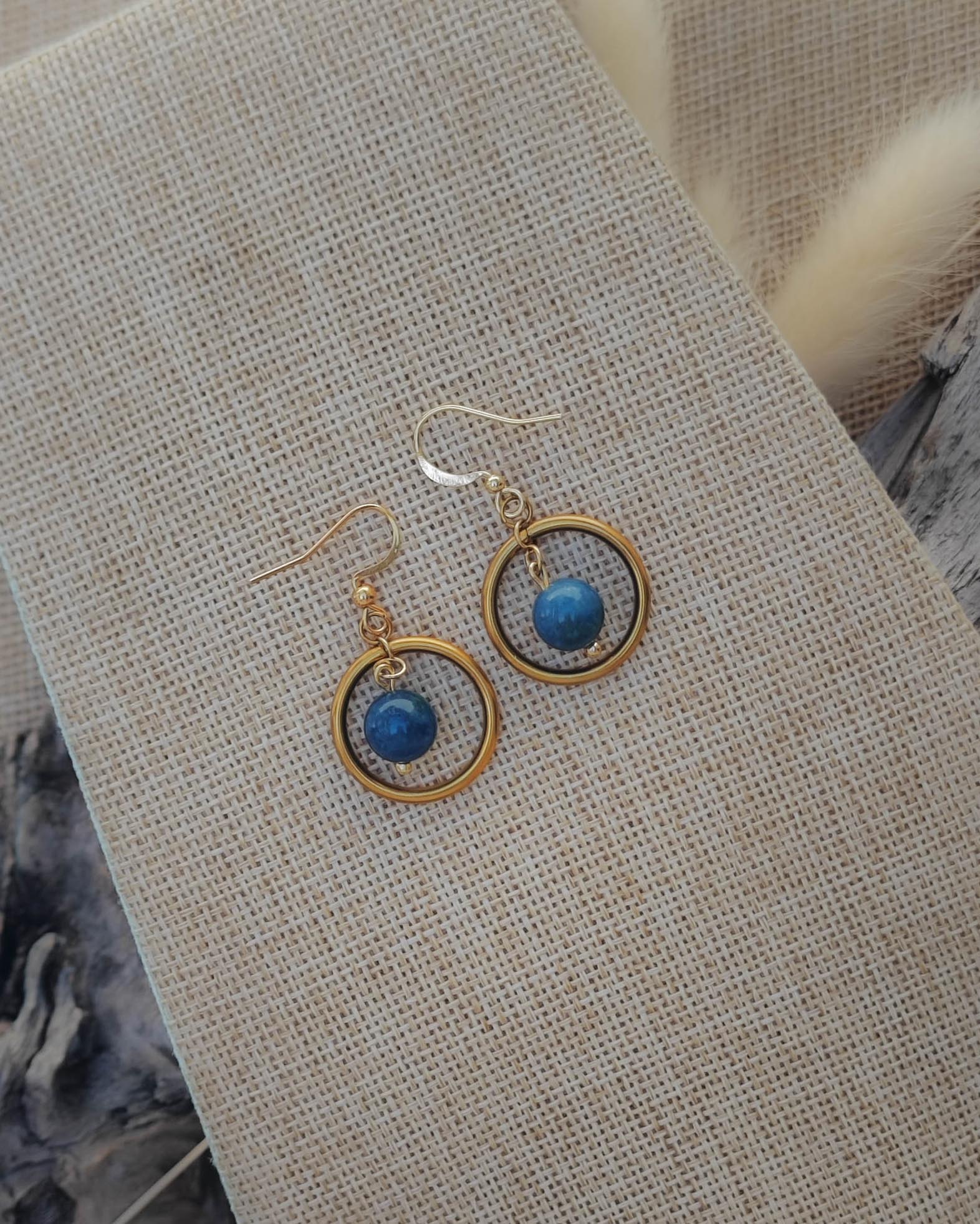 Vue de dessus des boucles d’oreilles Apatite créoles dorées avec détail du cercle et de la perle flottante
