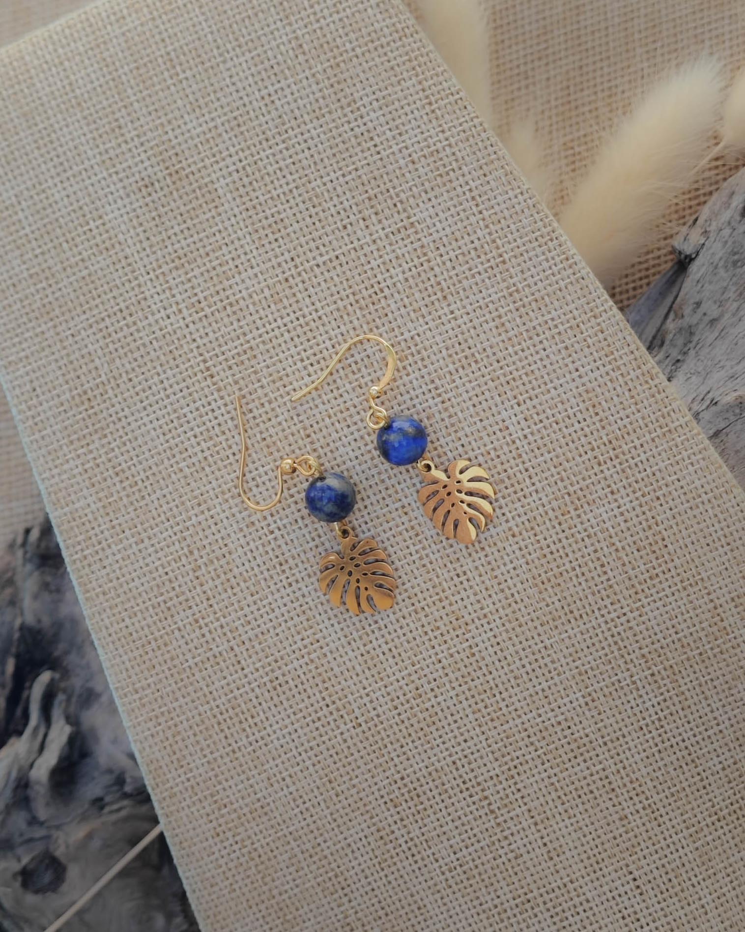 Vue de dessus des boucles d’oreilles Lapis Lazuli motif feuille dorée acier mettant en valeur la pierre et le détail du motif
