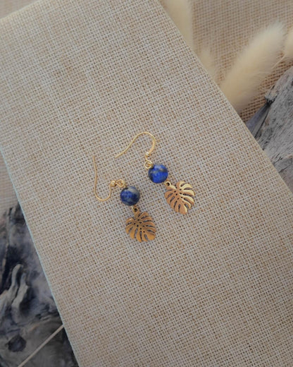 Vue de dessus des boucles d’oreilles Lapis Lazuli motif feuille dorée acier mettant en valeur la pierre et le détail du motif