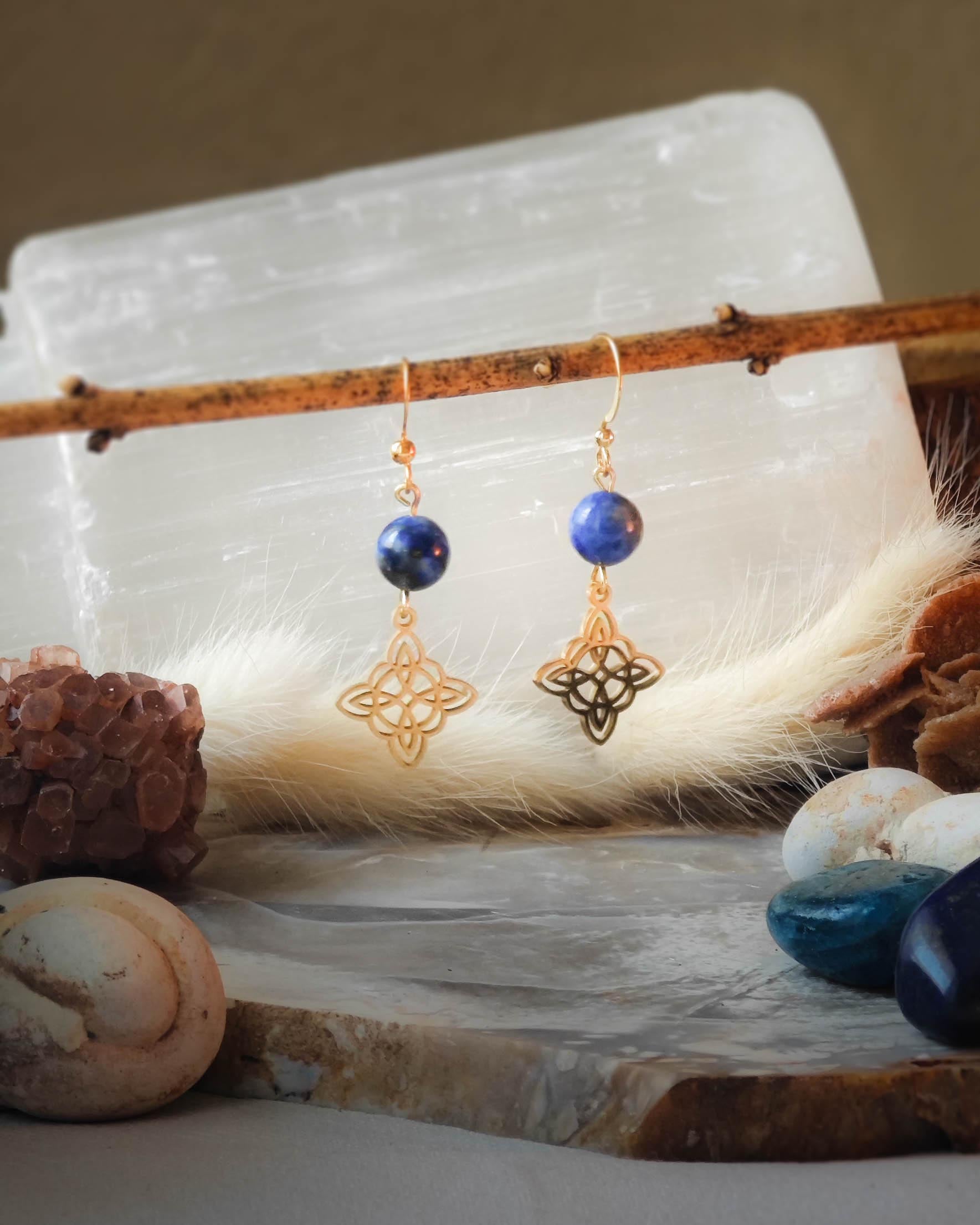 Boucles d’oreilles Lapis Lazuli motif Nœud des Sorcières doré sur roche plate avec pierres et épis blancs