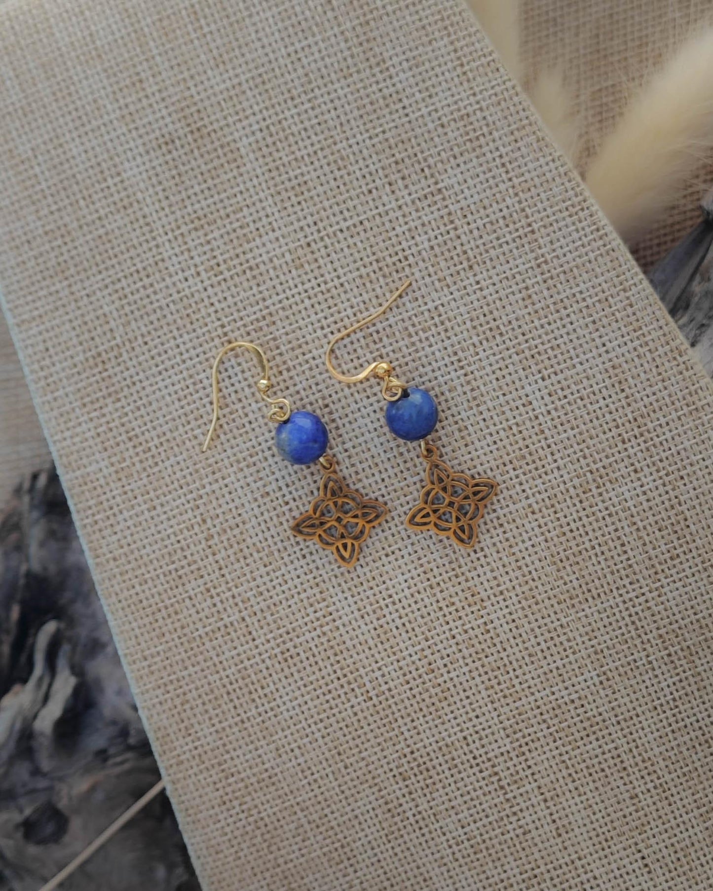 Vue de dessus des boucles d’oreilles Lapis Lazuli motif Nœud des Sorcières doré mettant en valeur la pierre et le détail du motif
