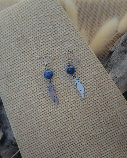 Vue de dessus des boucles d’oreilles Lapis Lazuli motif plume acier mettant en valeur la pierre et le détail du motif